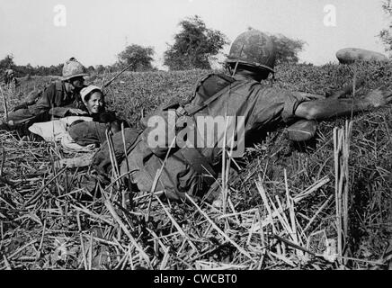 Vietnam War. Soldiers of the 1st Infantry Division protect a refugee mother and her children during a fight with Viet Cong. The Stock Photo