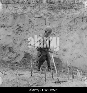Vietnam War. US Marine walks through a punji-staked gully. Punji stake booby traps were made out of wood or bamboo, and placed Stock Photo