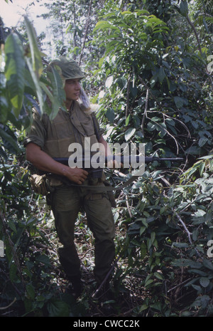 Vietnam War. US Marine moves through heavy grass in a deserted rice paddy while on patrol during a search and destroy operation Stock Photo