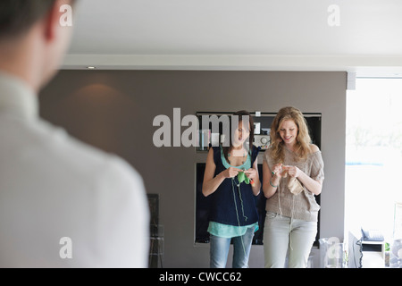 Man looking at two women knitting Stock Photo