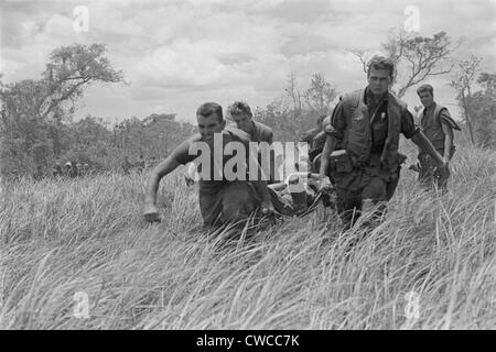 Vietnam War. While under heavy fire, US Marines are carry a wounded Marine to the evacuation helicopter near the Demilitarized Stock Photo