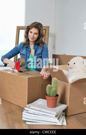 Woman taping up cardboard box Stock Photo