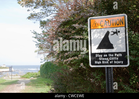 A caution sign instructing people to stay on a steep cliff path to avoid high risk of injury by falling off. Stock Photo