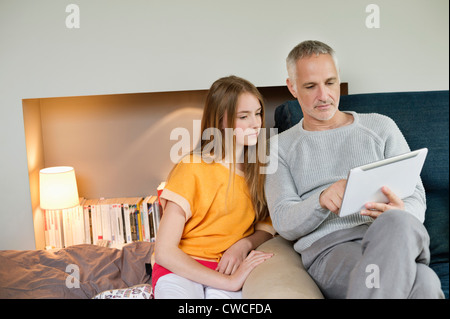 Man using a digital tablet with his daughter at home Stock Photo