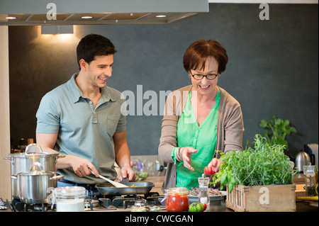 Woman assisting her son to cook food in the kitchen Stock Photo