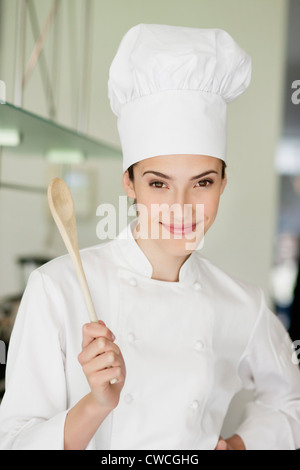 Happy female chef holding a wooden spoon Stock Photo