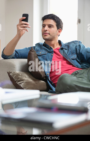 Man reclining on a couch and using a mobile phone Stock Photo