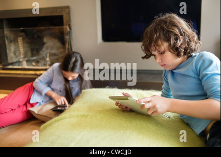 Boy and a girl using electronic gadgets at home Stock Photo