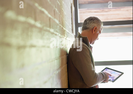 Man using a digital tablet near a window Stock Photo
