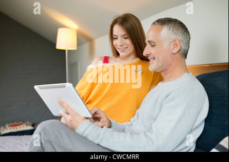 Man using a digital tablet with his daughter at home Stock Photo