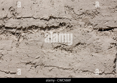 Render being applied to a straw covered building Stock Photo