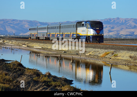 An Amtrak train crossing the Alviso Marina County Park during sunset, San Jose CA Stock Photo