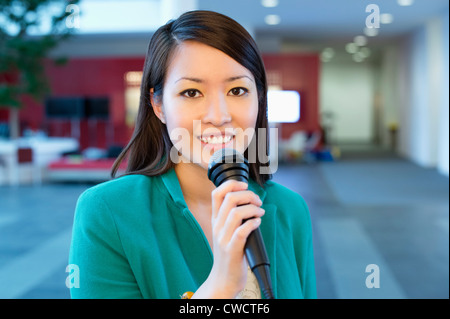 Portrait of a businesswoman holding microphone in an office Stock Photo