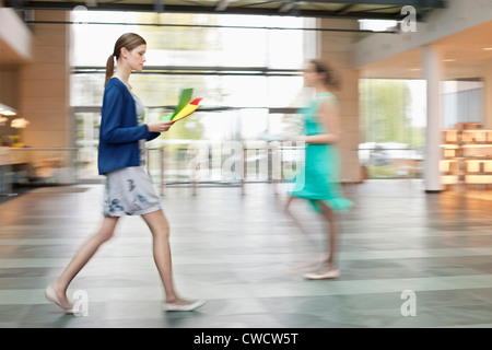 Businesswomen walking in an office lobby Stock Photo