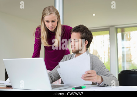 Woman looking at a man working on a laptop Stock Photo