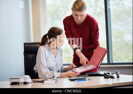 Businesswoman signing documents with her secretary Stock Photo