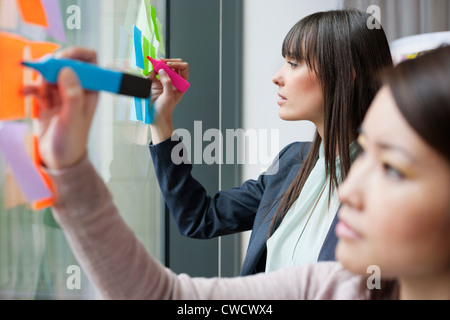 Businesswomen writing on adhesive notes in an office Stock Photo