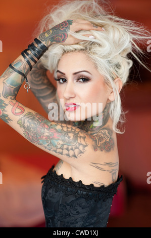 Portrait of tattooed young woman wearing corset with hands in hair Stock Photo