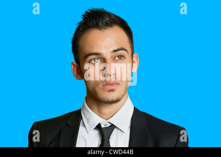 Thoughtful young businessman looking away over colored background Stock Photo