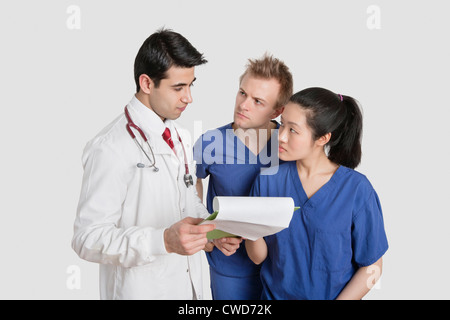 Multi ethnic healthcare professionals discussing medical report over gray background Stock Photo