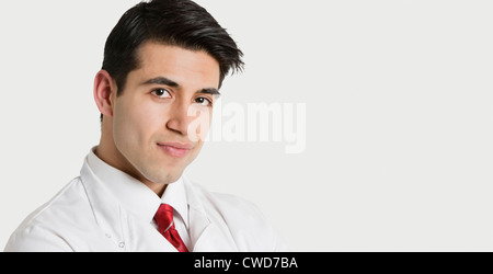 Close-up portrait of a handsome Indian male doctor smiling over light gray background Stock Photo