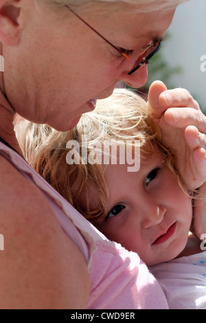Mother holds protecting against the sun's hand before her daughter Stock Photo