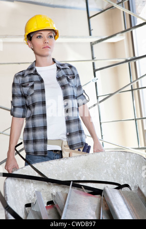 Female construction worker pushing a wheelbarrow full of bricks ...