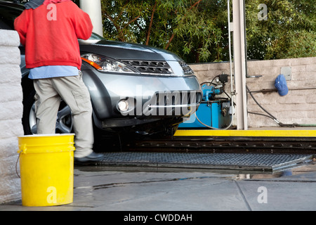 Car wash employee with vehicle on conveyor belt Stock Photo