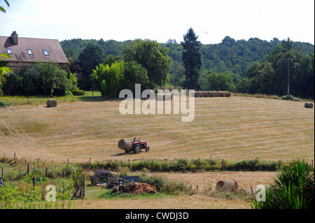 Tractor gathering hay bales on a farm in the Lot Region of South West France Europe Stock Photo
