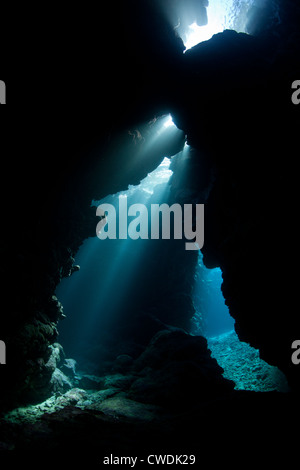 Sunlight cascades through cracks in a limestone reef.  Coral reefs have lots of three dimensional space that serve as habitats. Stock Photo