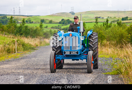 Enthusiast driving a blue vintage Fordson Power Major tractor during an Ayrshire Vintage Tractor and Machine Club road run. Stock Photo