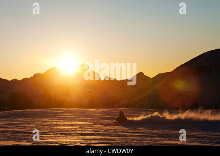 A athletic young man snowmobiling at sunset in Montana. Stock Photo