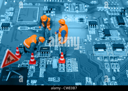 Miniature engineers fixing error on chip of circuit board. Computer repair concept. Close-up view. Stock Photo