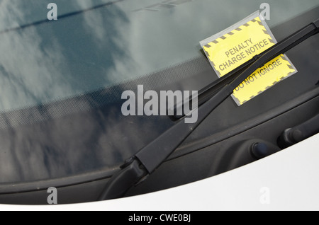Penalty Charge Notice under the windscreen wiper of a silver car. Stock Photo