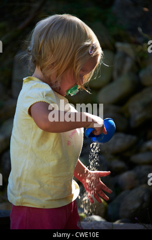 Child blond girl baby playing with sand in sandbox Stock Photo