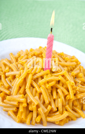 A plate of macaroni and cheese with a lit birthday candle to celebrate a pasta lover's birthday.