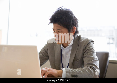 Businessman sitting and using laptop at desk Stock Photo
