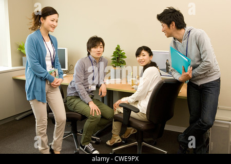 Four businesspeople in casual clothing talking at office Stock Photo