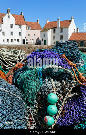 Pittenweem, East Neuk of Fife, Scotland, UK.   Fishing nets piled on the quayside with houses of a style typical to the area. Stock Photo