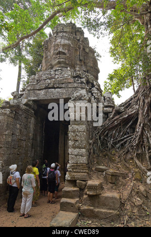 Vertical view of one of the stone faced gopura entrances to Ta Prohm or the Tomb Raider temple with tourists walking through. Stock Photo