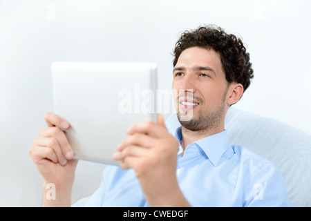 Young handsome man looking on a modern digital tablet. Studio shot. Stock Photo