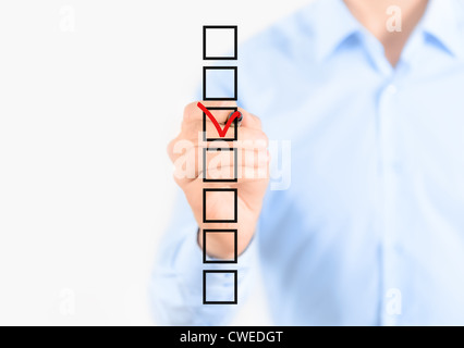 Young businessman checking mark on checklist with marker. Isolated on white. Stock Photo