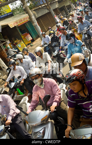 Horizontal view of chaotic rush hour traffic with hundreds of mopeds and their pillion passengers driving home. Stock Photo