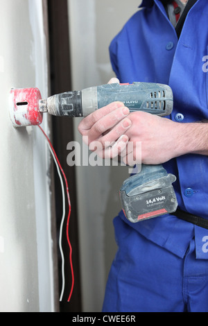 Man drilling a hole in a wall for an electrical socket Stock Photo