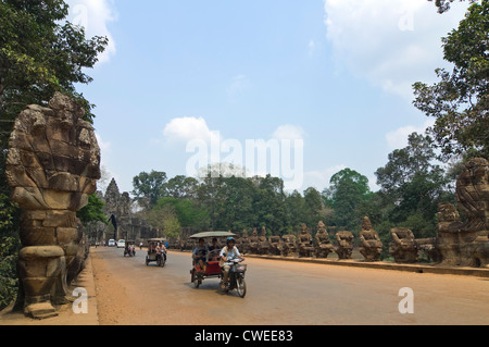 Horizontal view of tourists driving passed statues of Gods and Demons on the road to the Victory Gate at Angkor Thom, Cambodia Stock Photo