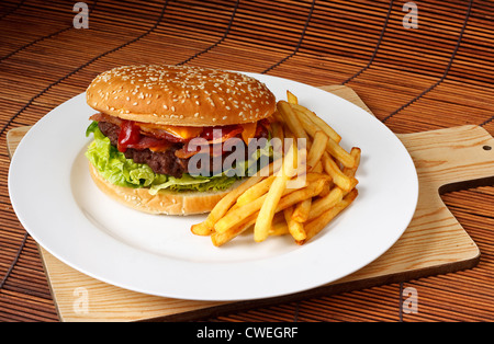 Bacon cheeseburger with a homemade beef patty on a bed of lettuce with a side of fries Stock Photo