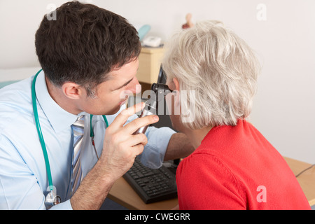 British doctor examining senior woman's ear Stock Photo