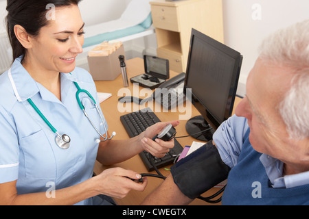 British nurse taking senior man's blood pressure Stock Photo