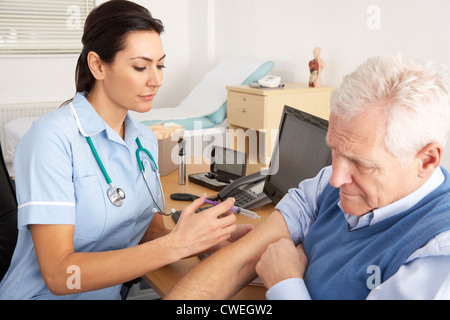 British nurse giving injection to senior man Stock Photo