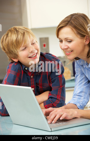 Mother and son using laptop in domestic kitchen Stock Photo